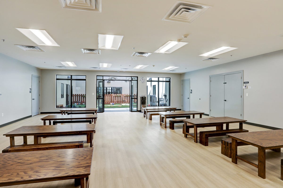 Activity room with wooden tables, benches, and a view of an outdoor play area, renovated by GSD Construction in Houston, TX