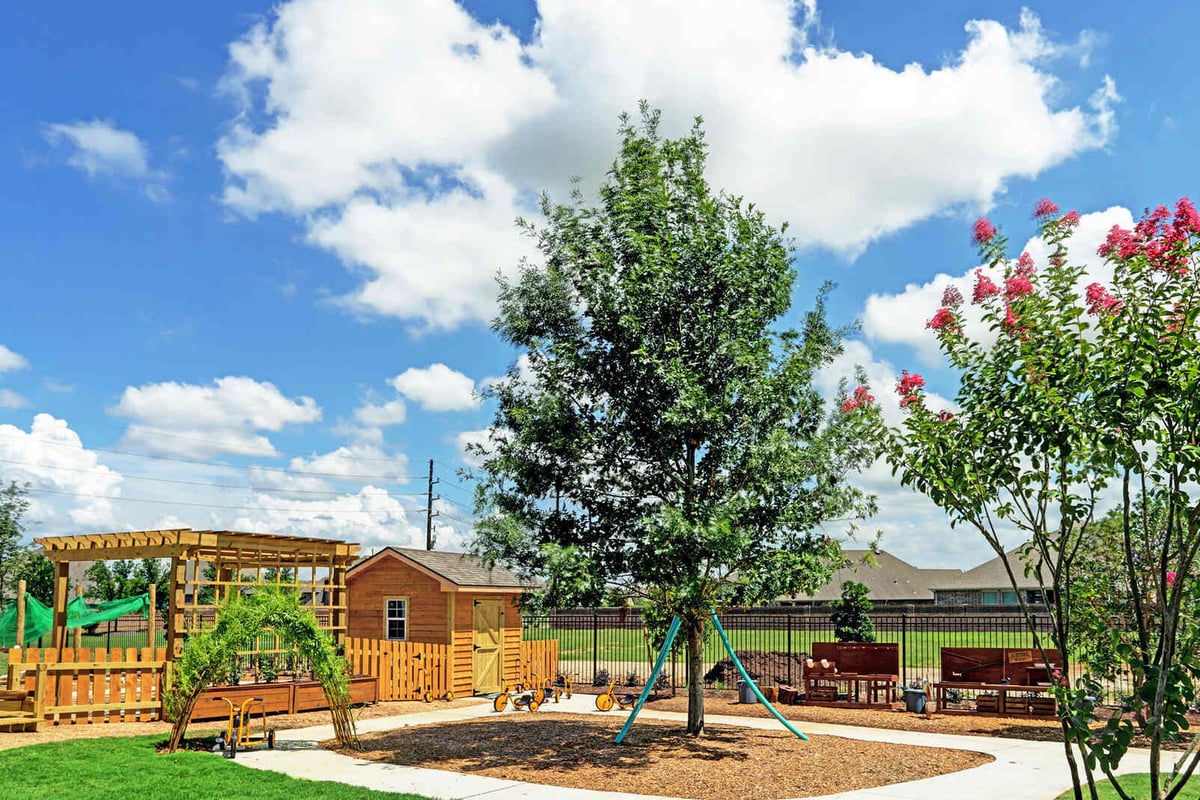 Outdoor play area with trees, colorful landscaping, and wooden structures, renovated by GSD Construction in Houston, TX