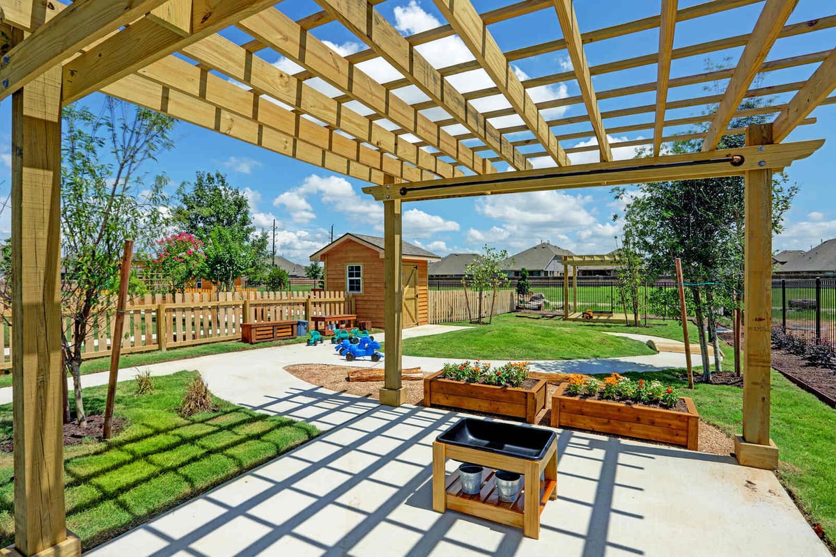Outdoor play area with wooden pergolas, planters, and lush green landscaping, completed by GSD Construction in Houston, TX