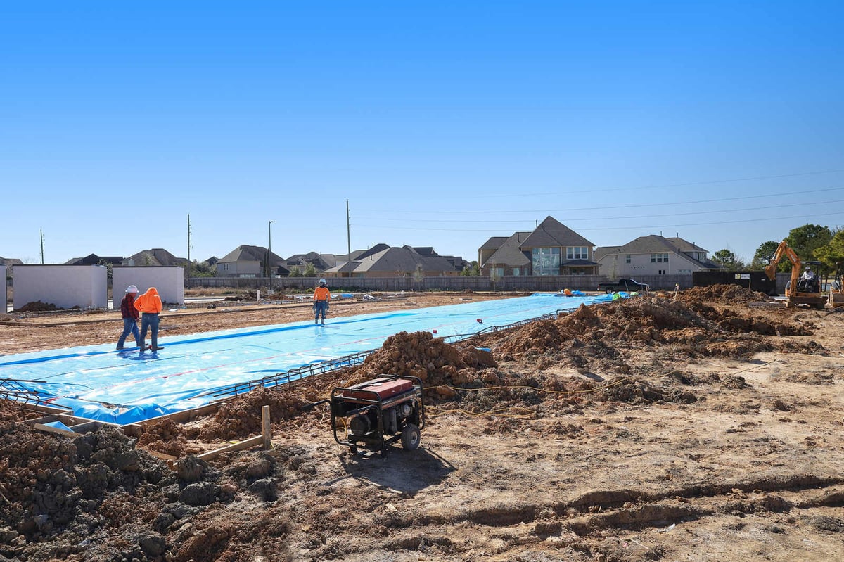 Construction site of a commercial building foundation with workers and heavy machinery in Houston, TX