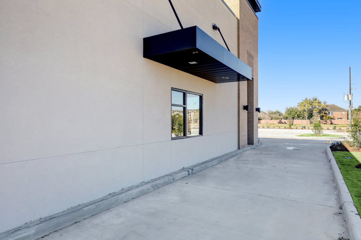 Drive-through area of a commercial building featuring a canopy and minimalistic design in Houston, TX