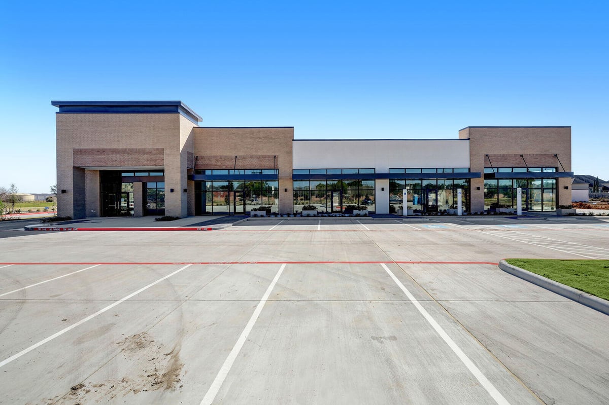 Newly constructed commercial building with large glass windows and a spacious parking area in Houston, TX