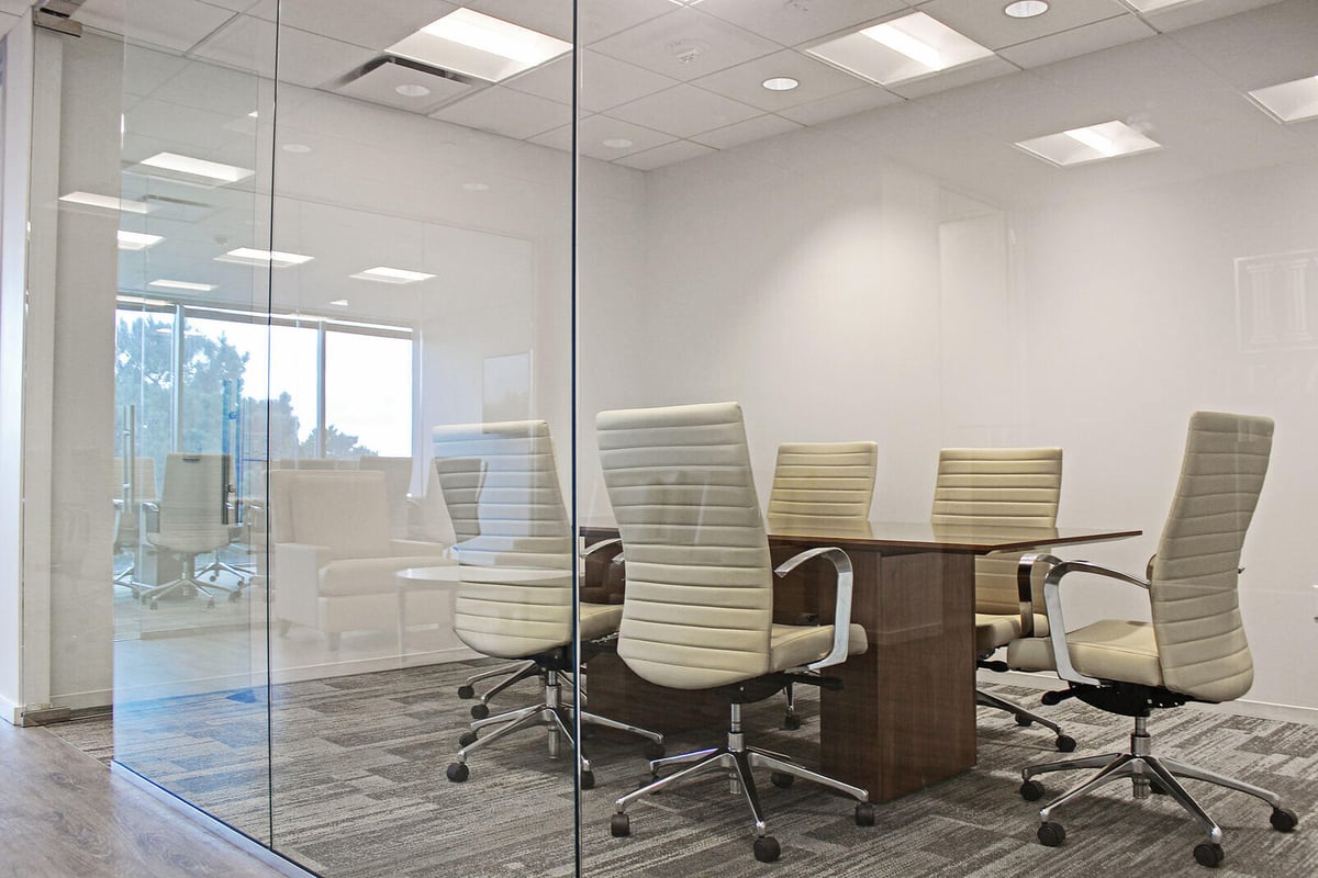 Conference room with glass walls and modern white chairs, part of a commercial renovation by GSD Construction in Houston, TX