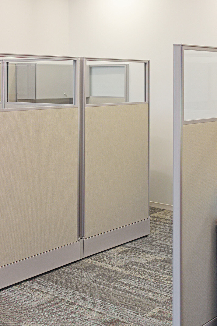 Private cubicle spaces with beige panels and gray carpeting in a commercial renovation by GSD Construction in Houston, TX